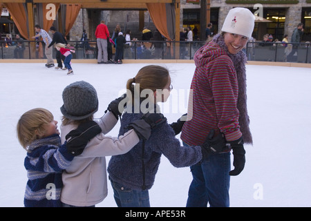 Una madre e tre bambini pattinaggio sul ghiaccio in una linea at Northstar ski resort vicino al lago Tahoe in California Foto Stock