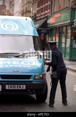 Un vigile emette i biglietti per il parcheggio di un furgone in Soho Londra Inghilterra REGNO UNITO Foto Stock