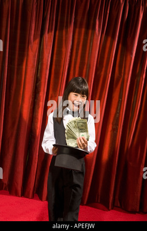 Ragazza asiatica tirando fuori il denaro del top hat Foto Stock