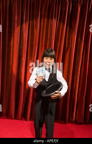 Ragazza asiatica tirando fuori il denaro del top hat Foto Stock