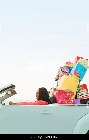 Donna africana nel convertibile con borse per lo shopping Foto Stock