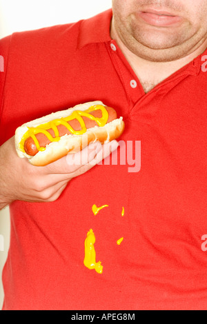 Uomo con hotdog e versare la senape sulla camicia Foto Stock