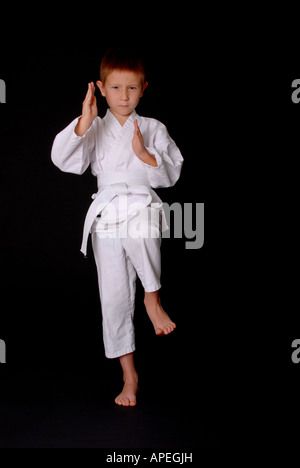 Giovane ragazzo nel karate outfit rendendo il movimento di combattimento Foto Stock