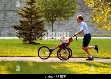 Genitore jogging con il bambino nel carrello Foto Stock