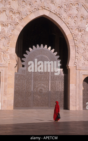 Signora musulmana che indossa un rosso abayas passa il Hassan 2 moschea in Marocco,i suoi mondi secondo più grande luogo islamico di culto Foto Stock