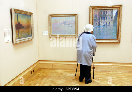 Visitatore guardando una mostra di Monet dipinti ad olio in una galleria presso il Museo Nazionale di Cardiff South Wales UK Foto Stock