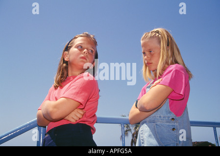 Due giovani ragazze della scuola 8-10 anni di età arrabbiato con ogni altro guarda oltre lo spallamento con espressione medio basso angolo di seguito dal signor ©Myrleen Pearson Foto Stock