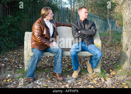 Un colore immagine orizzontale di due uomini seduti su una panchina avente un argomento.Essi potrebbero essere una coppia gay o solo agli amici. Foto Stock