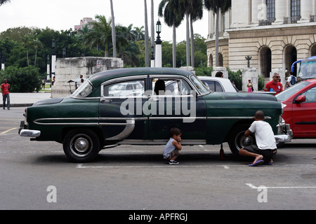 Il padre e il Figlio suo che fissa un pneumatico forato broken auto a La Havana Foto Stock