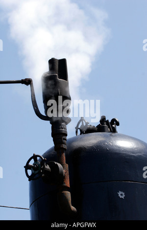 Un treno a vapore n. 4 con il fumo nero che lo circonda mentre viaggia attraverso la campagna di bruciare il suo fischio Foto Stock