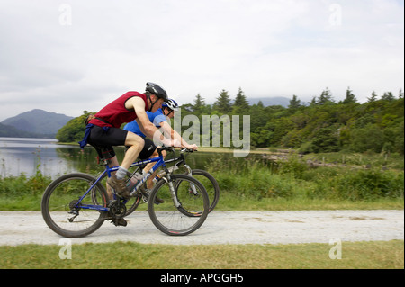 Due maschio mountain bike ciclo di ciclisti sul percorso vicino a Abbazia Mucross passato montagne e laghi di Killarney County Kerry Foto Stock