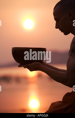 Uomo con il Tibetano Singing Bowl al tramonto Foto Stock