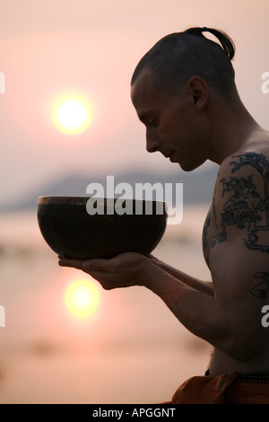 Uomo con il Tibetano Singing Bowl al tramonto Foto Stock