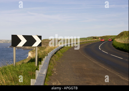 Bianco e nero chevron forte deviazione a destra cartello stradale nei pressi di curva pericolosa a strapiombo sulla A2 coast road vicino Dunluce Foto Stock