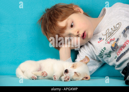 Ritratto di un giovane ragazzo che giace accanto a un sonno mongrel pup Foto Stock