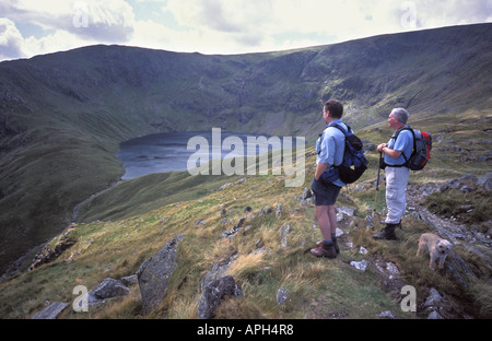 Gli escursionisti che si affaccia su acqua Blea tarn glaciale da High Street nel Parco nazionale del Lake District Cumbria Inghilterra England Foto Stock