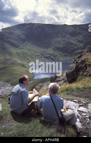 Walkers controllare mappa affacciato su acqua Blea tarn glaciale da High Street nel Parco nazionale del Lake District Cumbria Inghilterra England Foto Stock