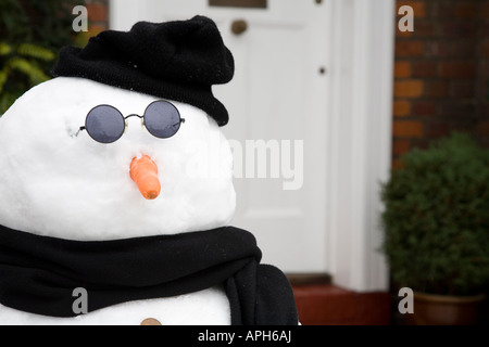 Pupazzo di neve davanti alla porta di una casa tradizionale Foto Stock
