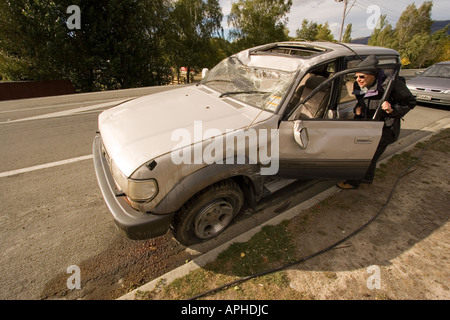 Nuova Zelanda esaminando driver danneggiato o soggetto ad atti vandalici auto sulla strada Foto Stock