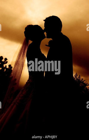 Sposa e lo sposo abbraccio dopo il matrimonio in silhouette al tramonto Foto Stock