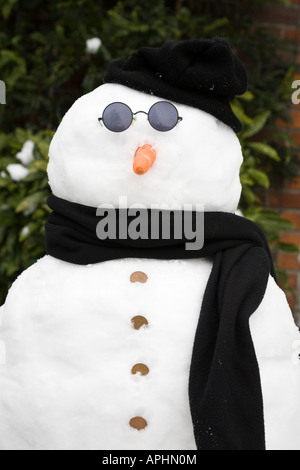 Vero pupazzo di neve indossando occhiali da sole e cappello e sciarpa Foto Stock