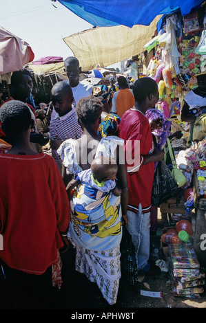 Una donna africana cammina con il suo bambino sulla schiena attraverso il mercato in Serrekunda la città più grande del Gambia Foto Stock