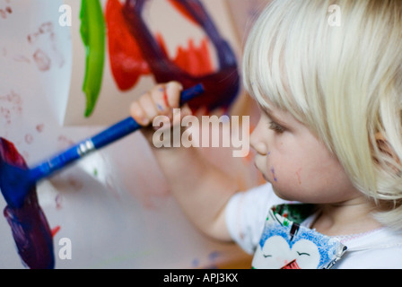 Stock Foto di un bambino di due anni la pittura di un'immagine sta utilizzando un pennello di colore blu Foto Stock