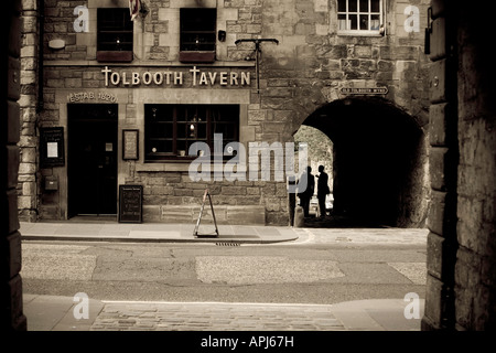 La Old Tolbooth Tavern in Edinburgh Royal Mile con due persone in silhouette in Wynd Foto Stock