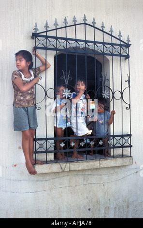 Bambini alla finestra per la loro casa a San Sebastian Retalhuleu Guatemala in attesa per la processione di passare Fiesta celebrazioni Foto Stock