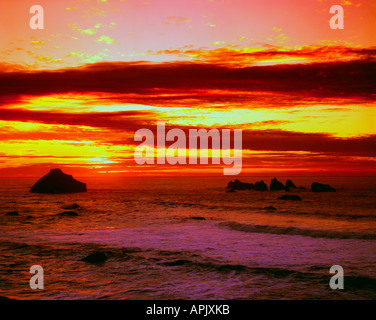 Cielo di tramonto illumina come il sole scende sulla faccia Rock sul fronte oceano a Bandon sul litorale di Oregon Foto Stock