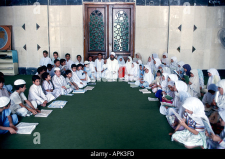 IRAQ BAGHDAD Imam al-un'dprosciutto moschea scuola islamica ragazzi e ragazze in abito tradizionale studiare il Corano con il loro Imam Foto Stock