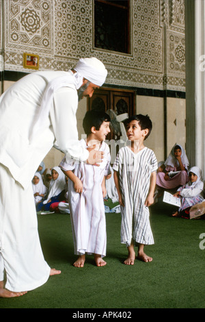 IRAQ BAGHDAD Imam al-un'dprosciutto moschea scuola islamica cinque anno old boys recitare brani del Corano per loro Imam mentre la ragazza Foto Stock