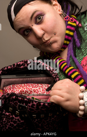 Giovani chubby punk donna con faccia forato che mostra il contenuto della sua borsetta Foto Stock