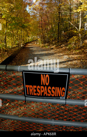 Nessun segno di trasgressione e il cancello chiuso prima di un bosco country road Foto Stock