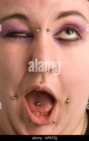 Giovani punk goth welsh donna; ha più piercing al viso UK winking fotocamera a bocca aperta linguetta forata Foto Stock