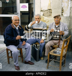 Un gruppo di tre locali bagno turco-cipriota uno degli uomini con valigetta ai suoi piedi relax di bere il caffè in Nicosia Cipro del Nord Foto Stock