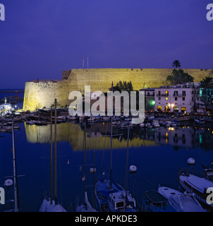 Crepuscolo vista delle mura del castello illuminato dai fari di lavoro ad alta intensità luminosa e riflettendo nel porto di Kyrenia città turca di Cipro del Nord Foto Stock