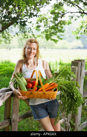 Donna che mantiene fresche e vegetali cestello (verticale). Foto Stock