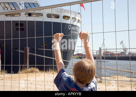 Germania, Amburgo, ragazzo (4-5) guardando la Queen Mary 2 sul fiume Elba Foto Stock