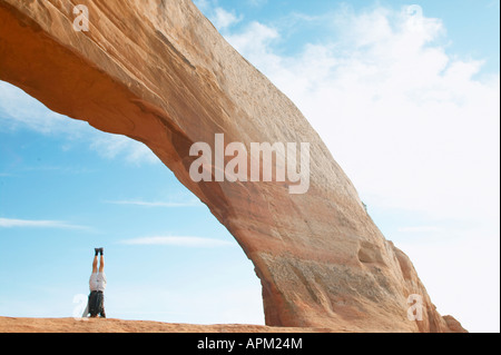 Uomo in piedi sulla testa sotto roccia arcuata Foto Stock