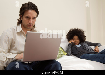 Giovane uomo utilizzando laptop e la Donna che parla al telefono Foto Stock