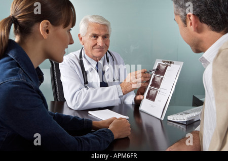 Dottore in office spiegando di scansione ad ultrasuoni per un giovane medico con il paziente in ufficio Foto Stock