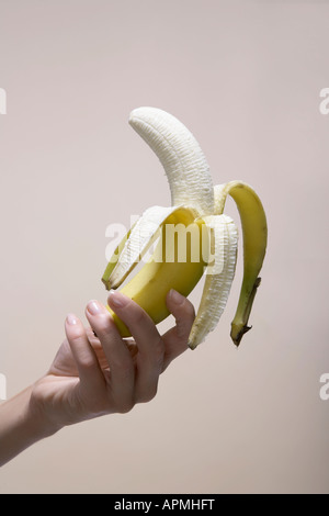 Donna di mano azienda sbucciata banana (close-up) Foto Stock