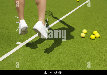 Giocatore di Tennis jumping vicino a palle da tennis (focus su piedi) Foto Stock