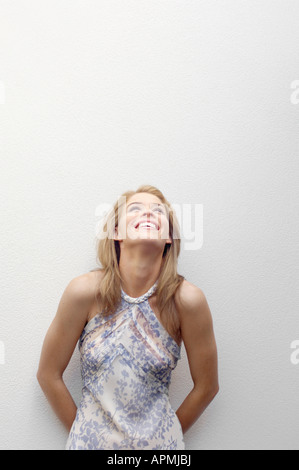 Giovane donna appoggiata sulla parete e ridere (verticale). Foto Stock
