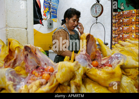 Una donna prende una chiamata telefonica mentre si lavora in un pollame macelleria vendere appena macellata polli in Antigua Guatemala s cen Foto Stock