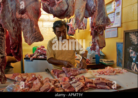 Un uomo rivestimenti di tagli di carni bovine durante il lavoro presso un macellaio in stallo il mercato centrale di Antigua Guatemala 2005 Foto Stock