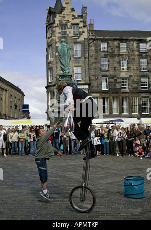 Edinburgh Fringe street performer sul monociclo e giovane ragazzo salto per contanti, Scozia UK Europa Foto Stock