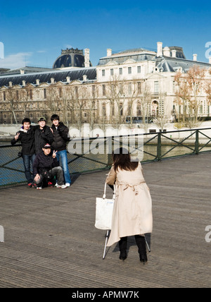 Un gruppo di giovani turisti asiatici in posa per una fotografia sul Pont des Arts al di fuori del Louvre, Parigi, Francia, Europa Foto Stock