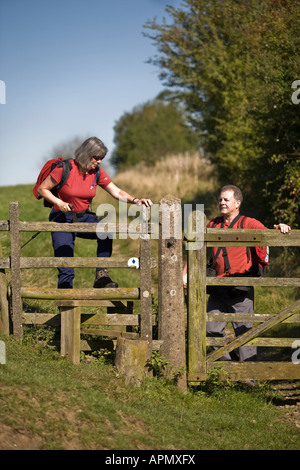 Due escursionisti di Cotswold campagna arrampicarsi su un montante verticale in estate, Bledington, Gloucestershire, Regno Unito Foto Stock